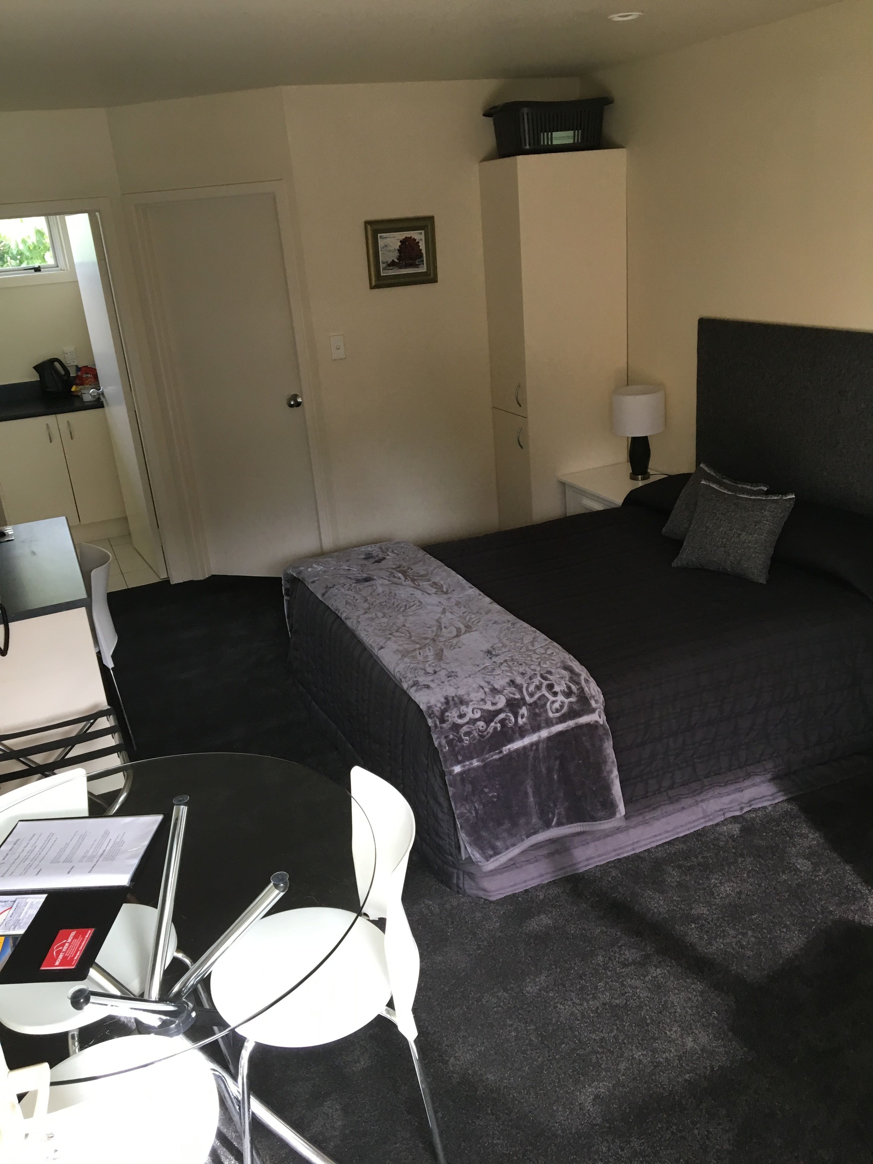 Habitación de hotel con cama, escritorio, silla, una mesita y una lámpara.
