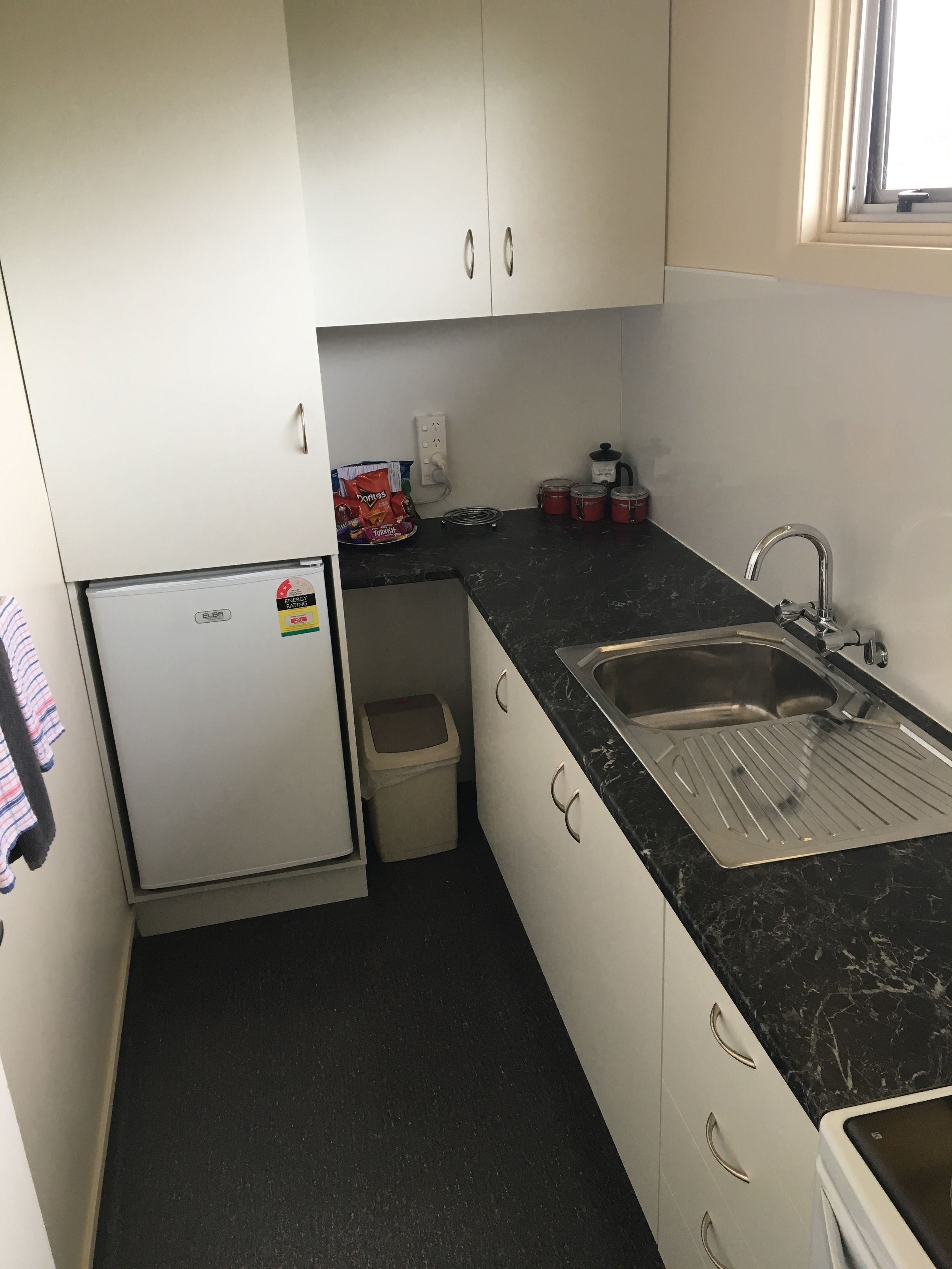 A compact kitchen with a refrigerator, sink, and countertop.