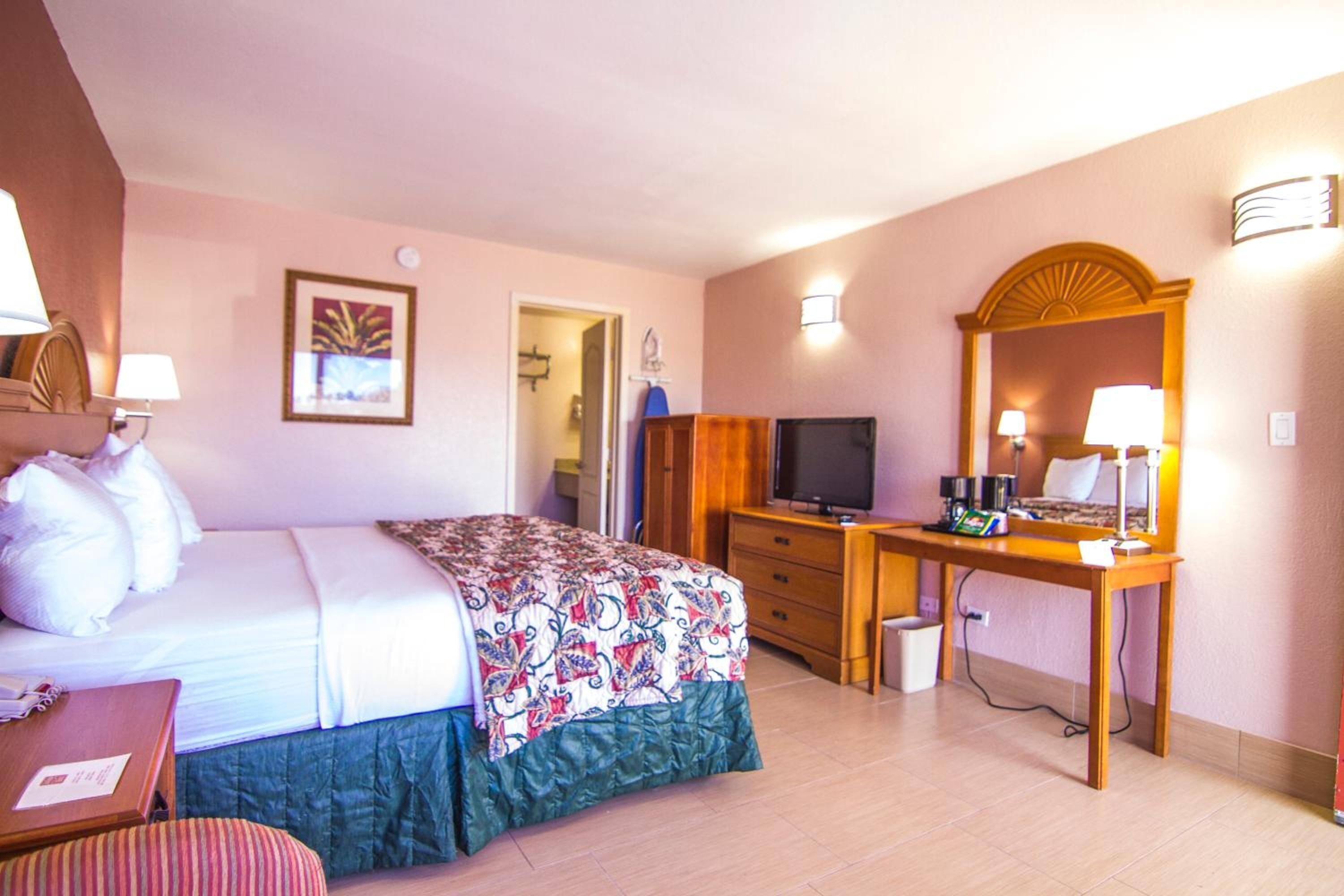 A hotel room with a bed, a desk, a television, and a mirror.