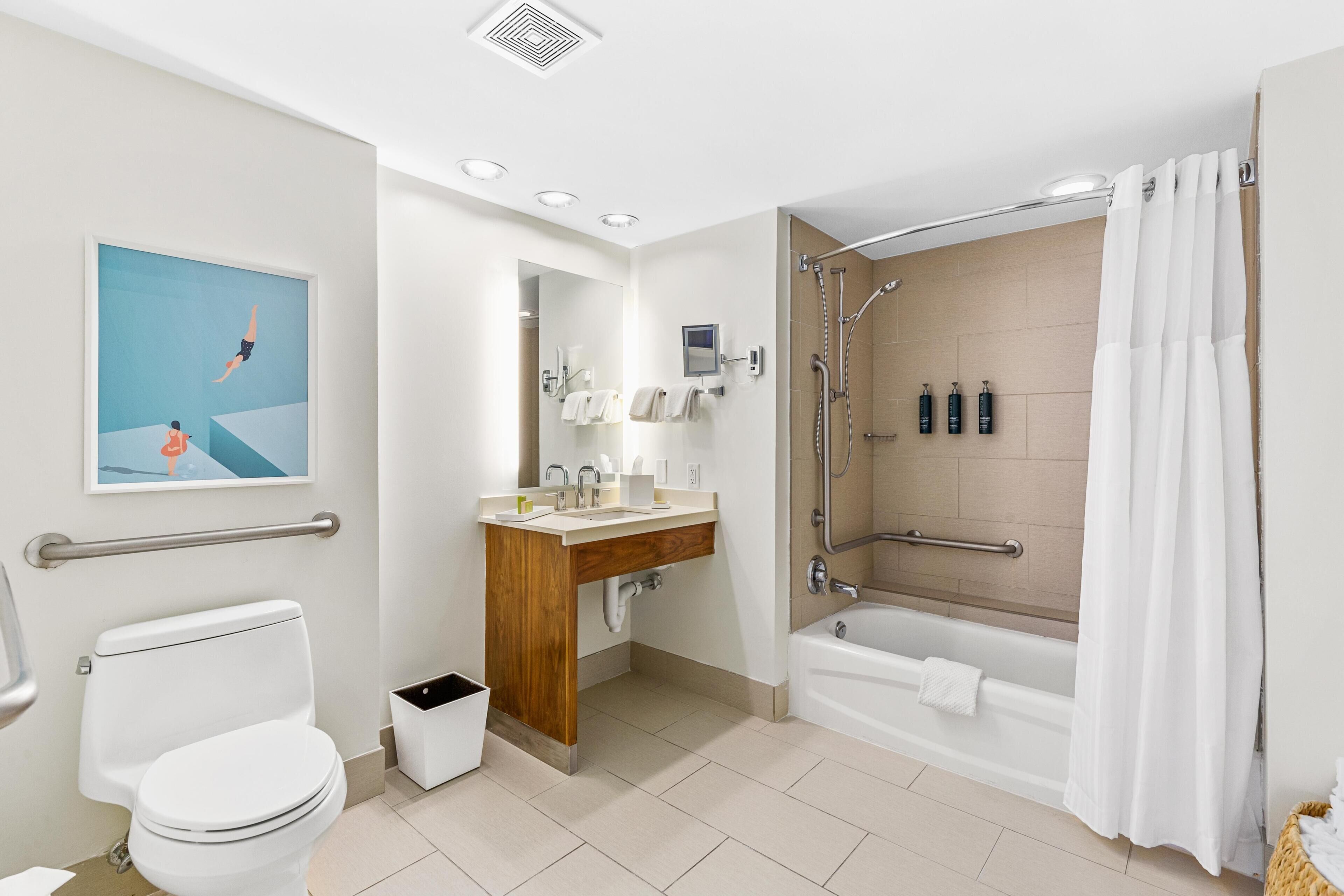 Een moderne badkamer met toilet, wastafel, douche en een ingelijst kunstwerk aan de muur.