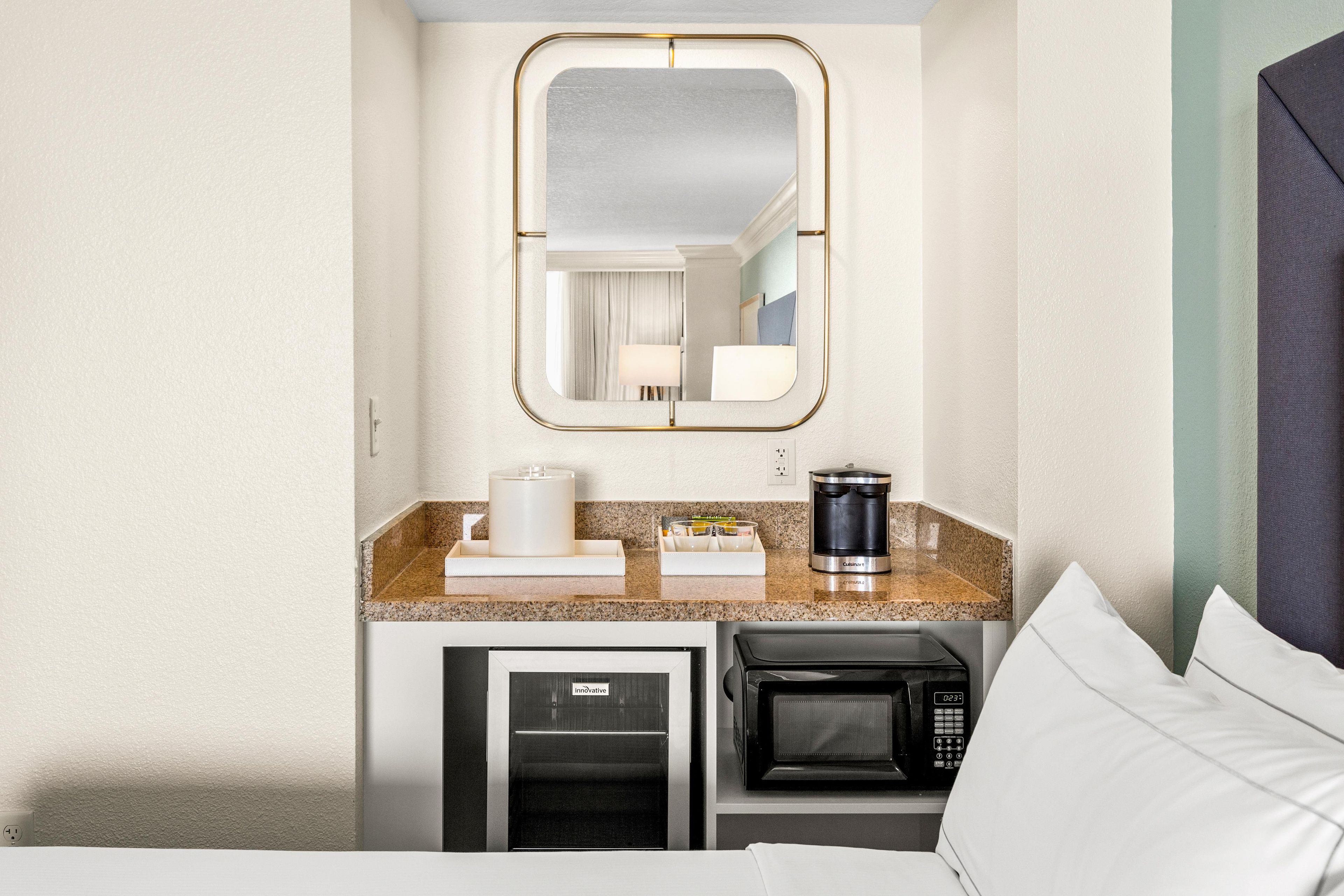 A compact hotel room with a kitchenette, a microwave, a coffee maker, and a small refrigerator.