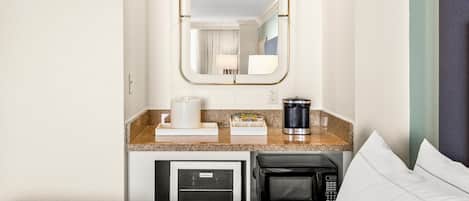 A compact hotel room with a kitchenette, a microwave, a coffee maker, and a small refrigerator.