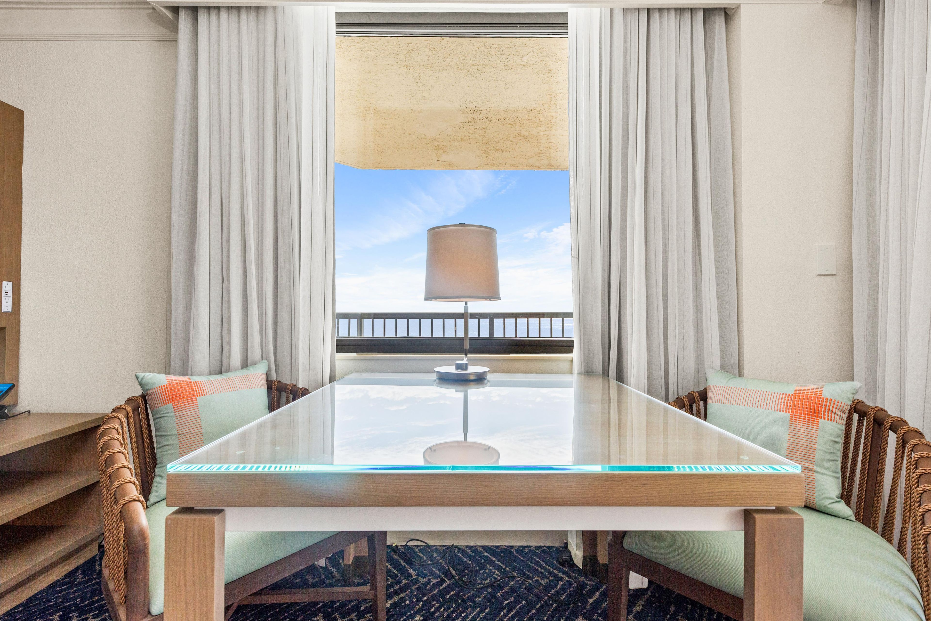 Una habitación de hotel con un ventanal grande, una mesa con sillas y vistas al mar.