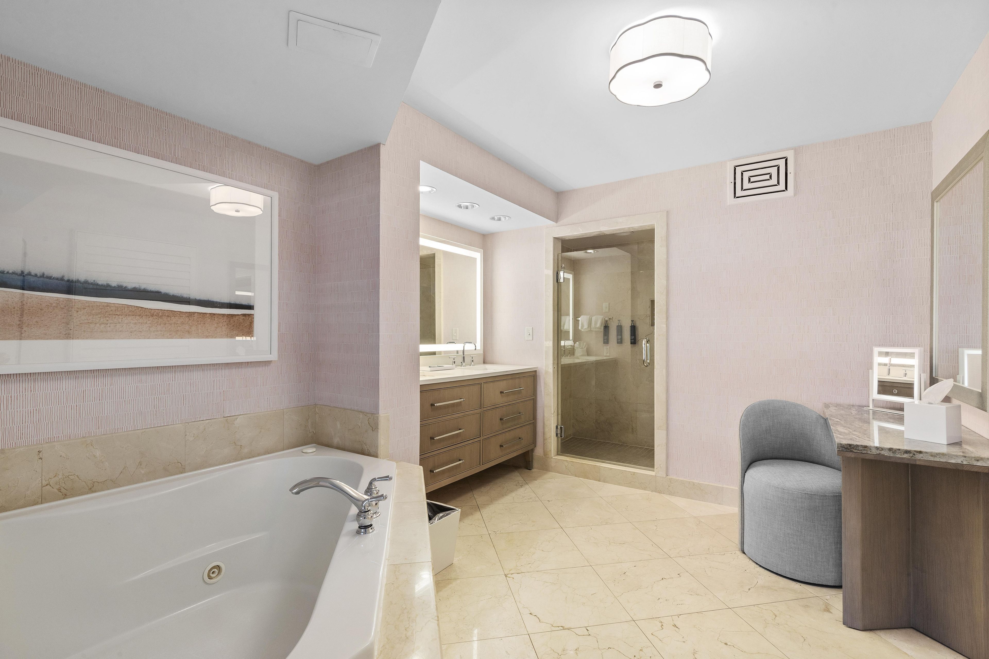 A modern bathroom with a large bathtub, a walk-in shower, and a vanity with a mirror.