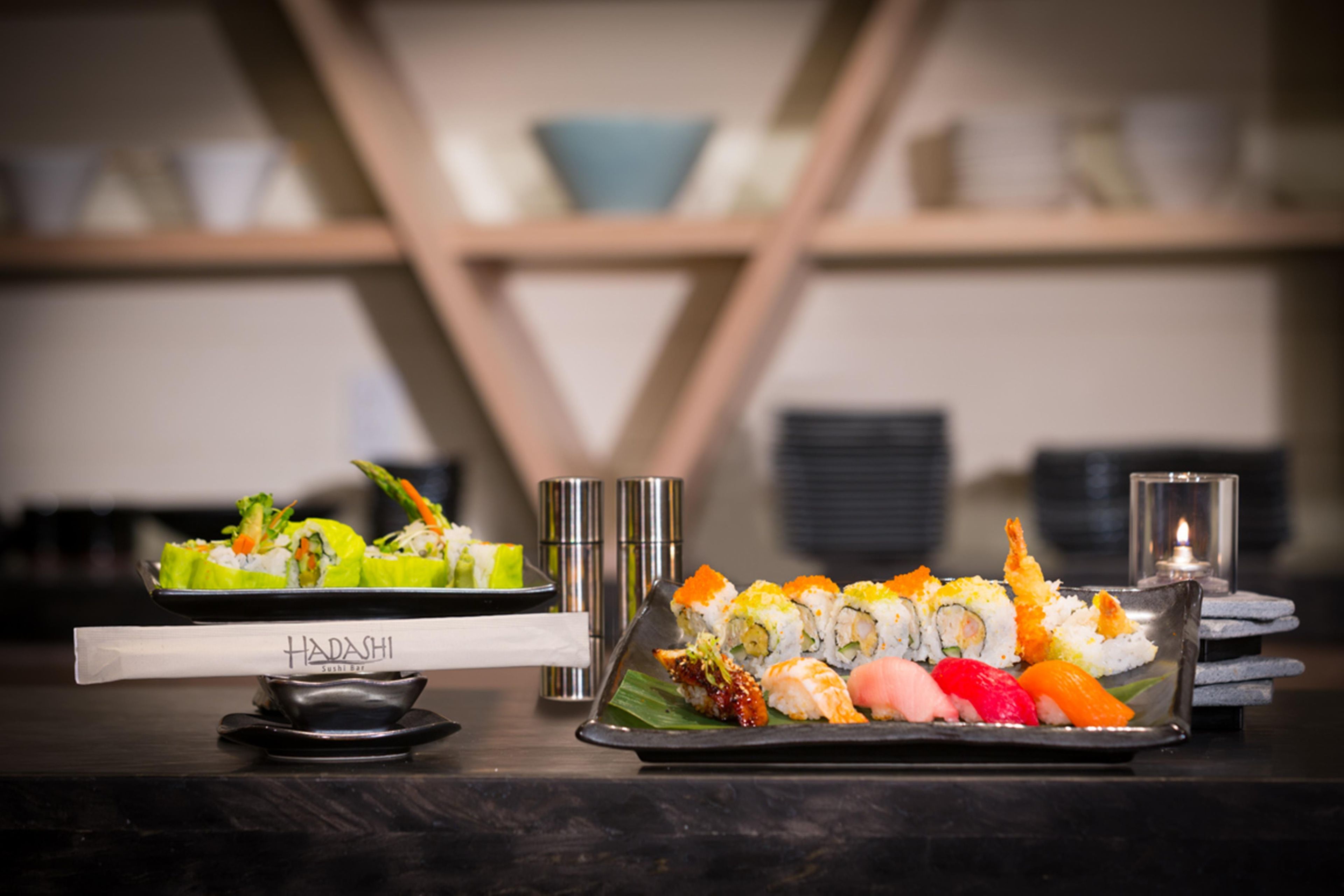 Un bar de sushi con distintos tipos de sushi expuestos en bandejas.
