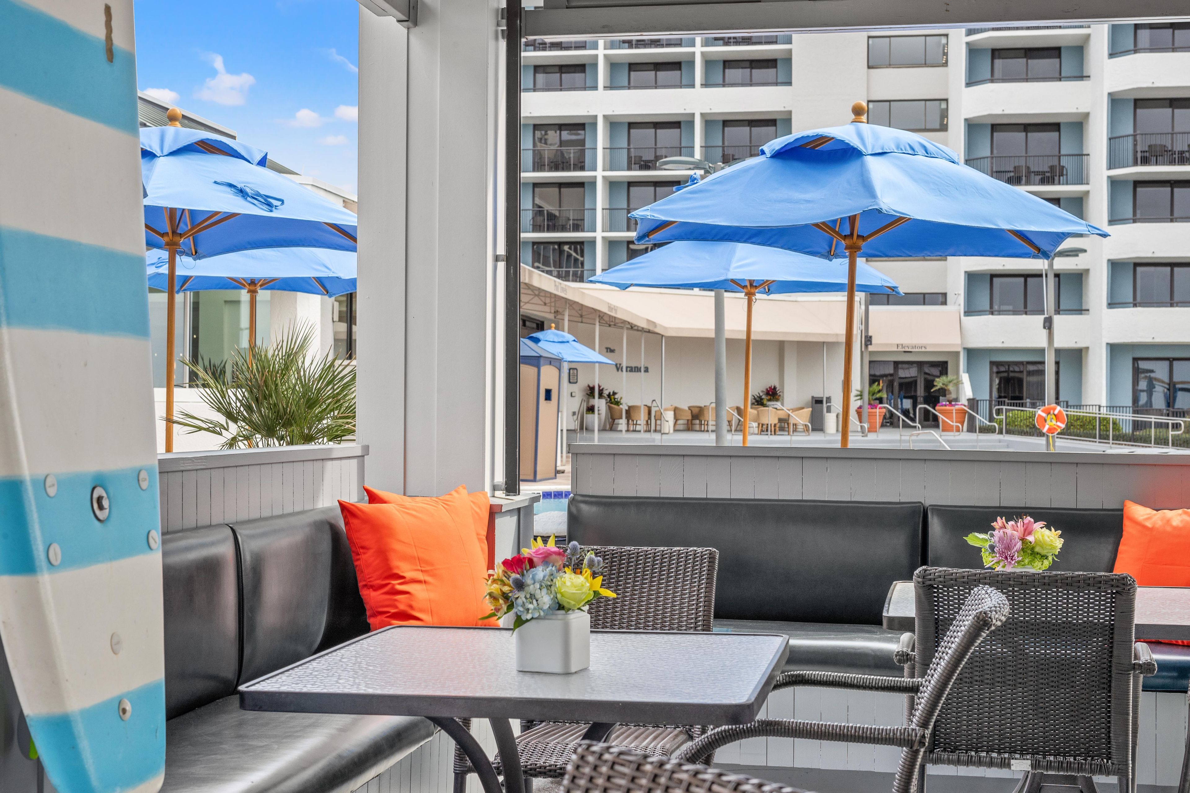 An outdoor seating area with tables, chairs, and blue umbrellas.