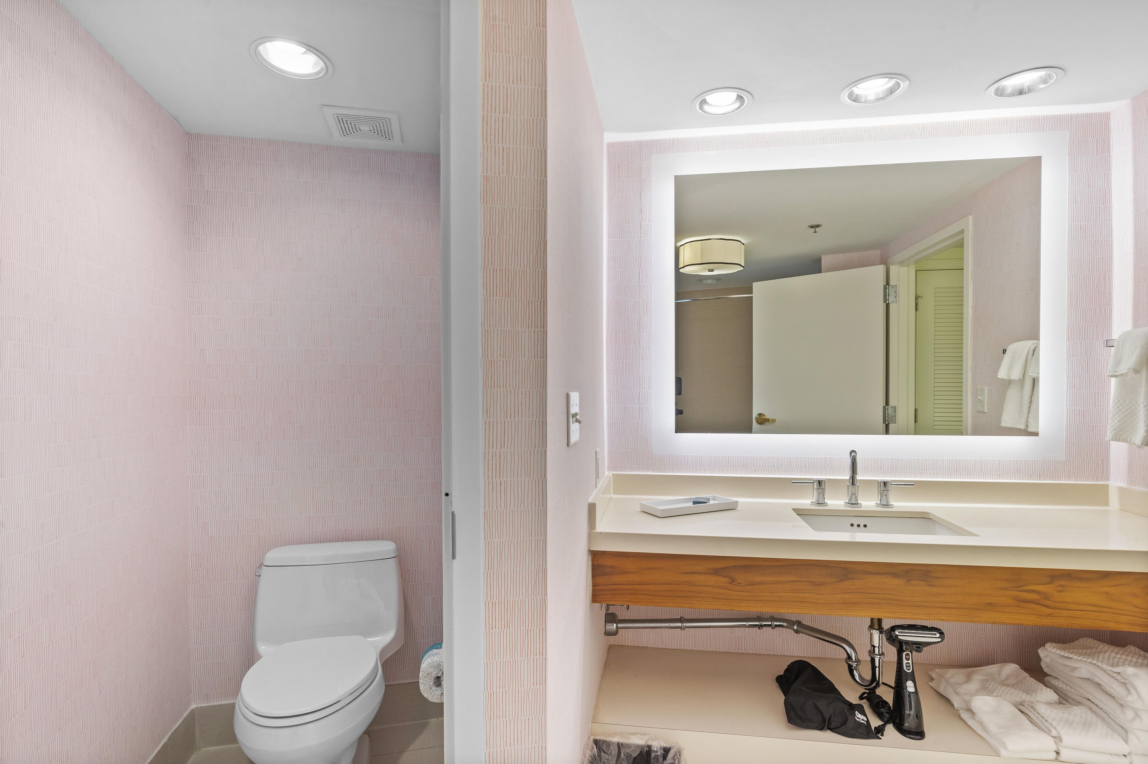 Un baño con inodoro, lavamanos, espejo y cabina de ducha.