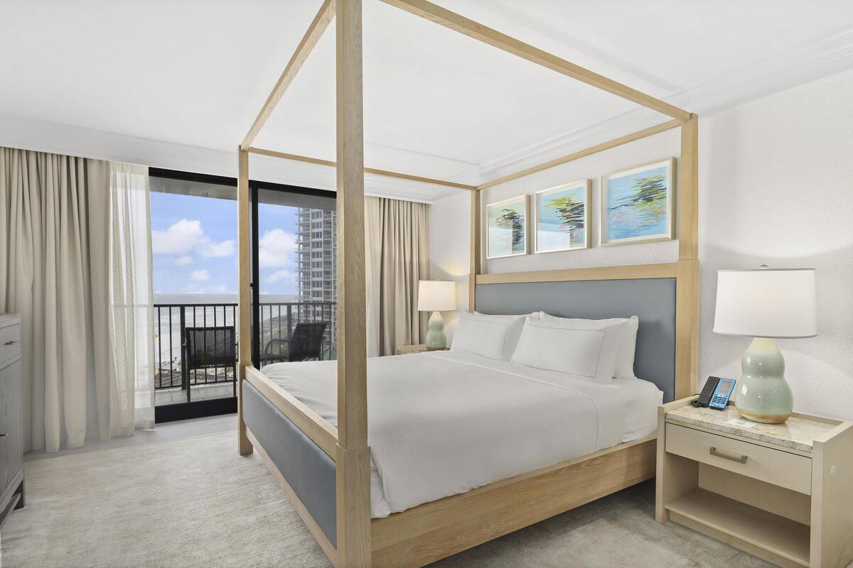 A four-poster bed with a nightstand, a lamp, and a phone on the bedside table.