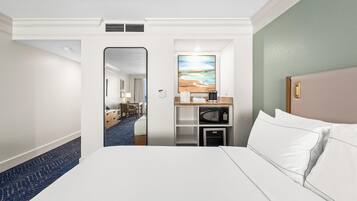 Una habitación de hotel con una cama, microondas, una pequeña cocina y un cuadro en la pared.