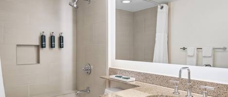 A modern bathroom with a bathtub, a shower, and a sink with a granite countertop.
