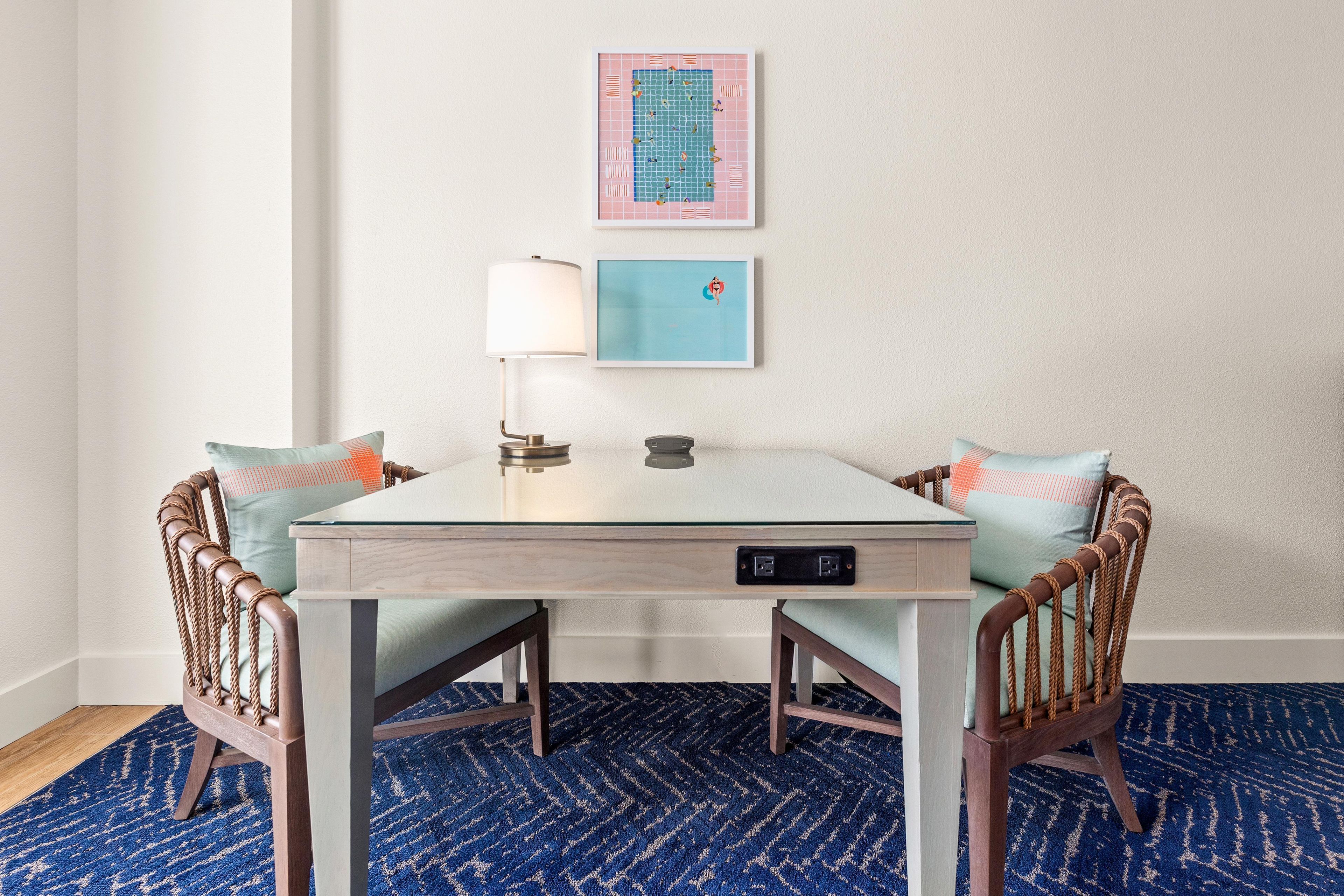 A small dining area with a table, chairs, and two wall-mounted artworks.