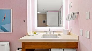 A bathroom with a large mirror, a sink, and a toilet.