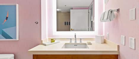 A bathroom with a large mirror, a sink, and a toilet.