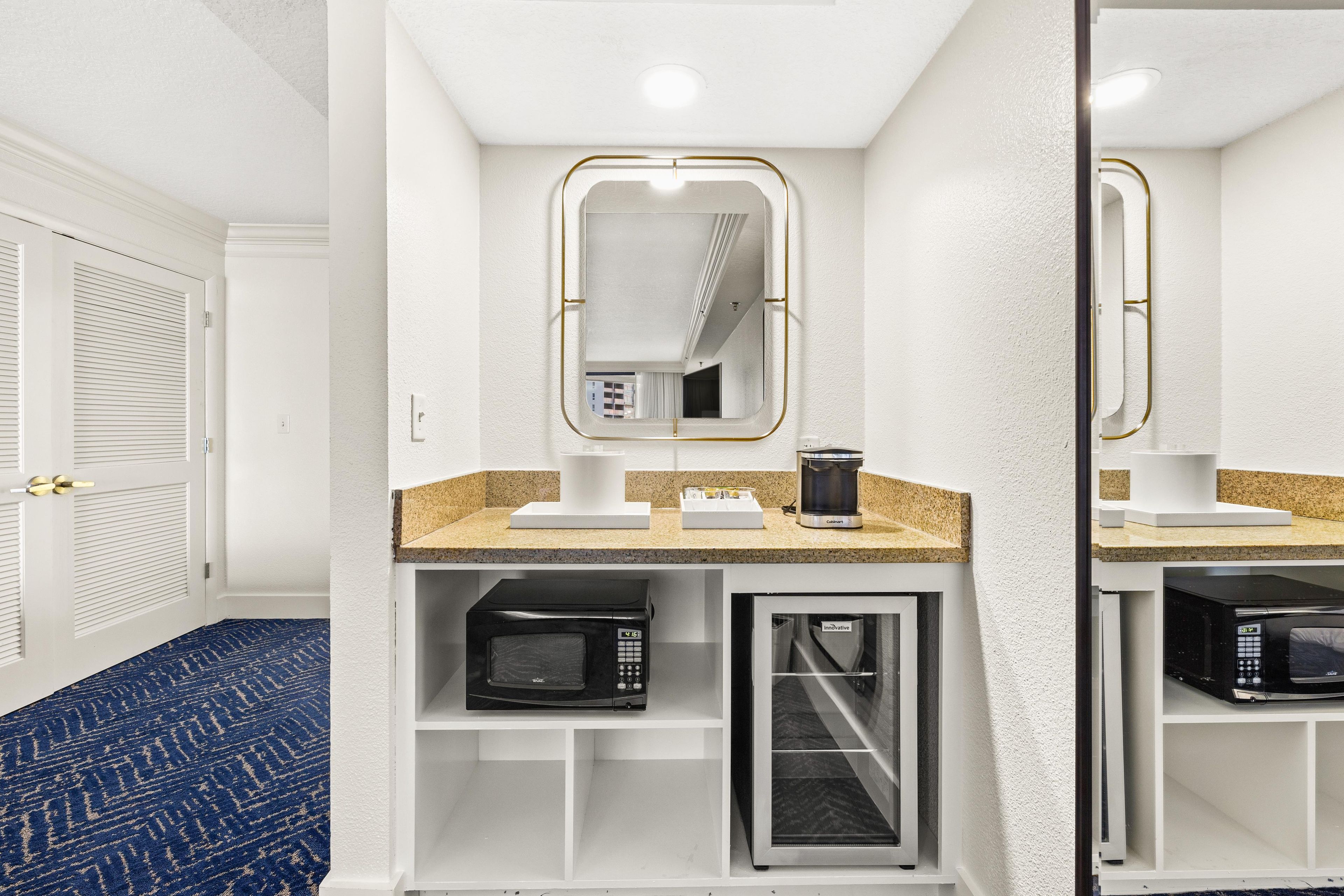 A hotel bathroom with a mirror, a coffee maker, and a microwave.