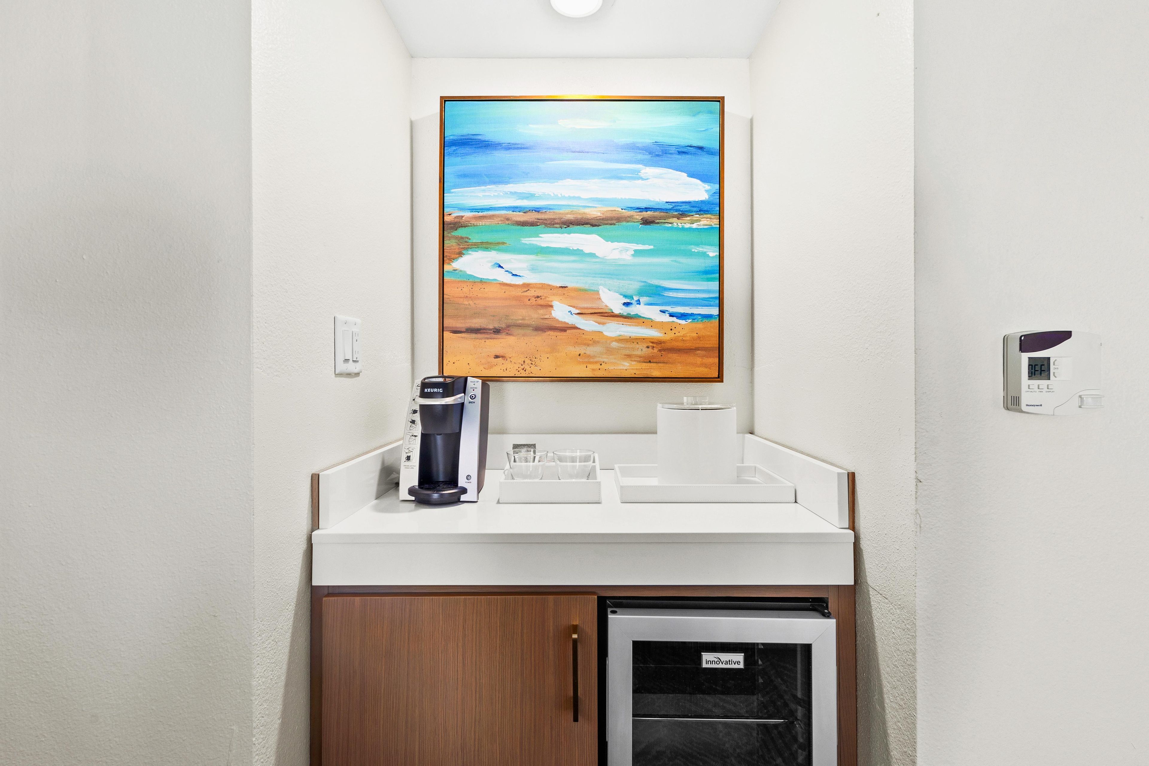 A bathroom with a coffee machine, a sink, and a small refrigerator.