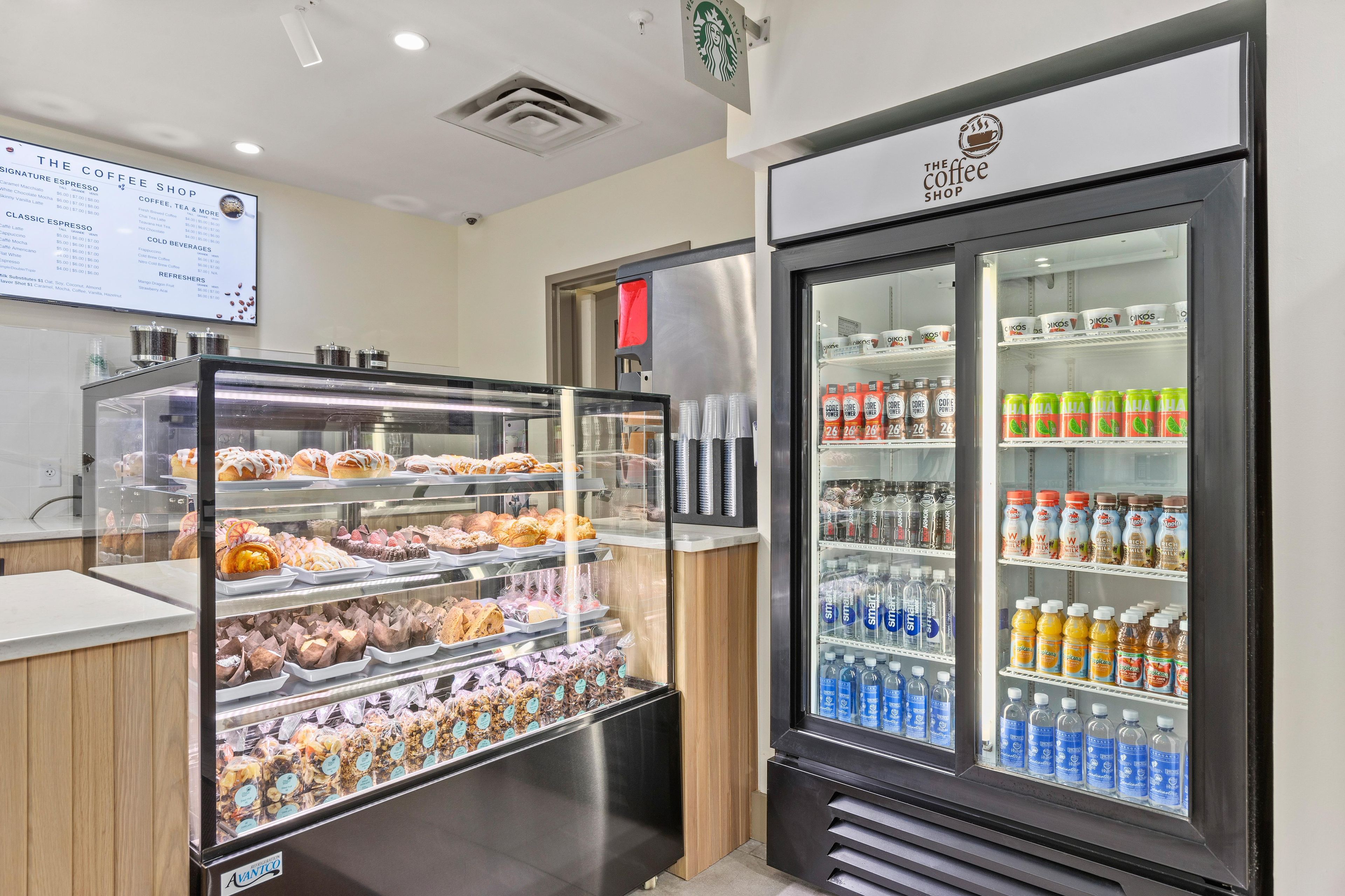 A coffee shop with a display case of pastries and a refrigerator stocked with beverages.