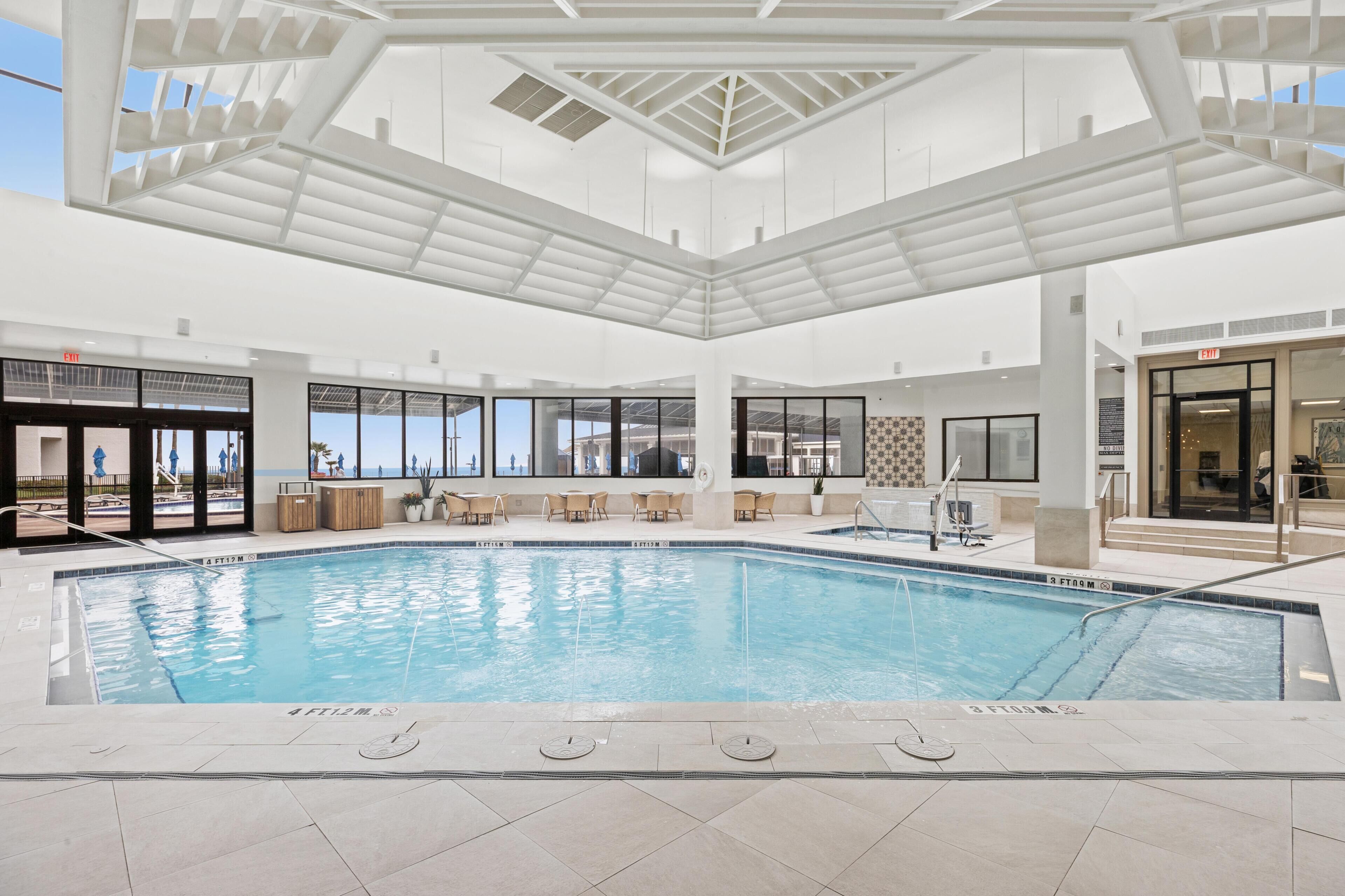 Une piscine intérieure offrant une vue dégagée sur le ciel, entourée d’espaces de détente et dotée d’une architecture moderne.