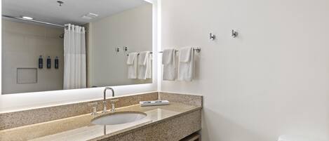 A modern bathroom with a large mirror, a sink, and a toilet.