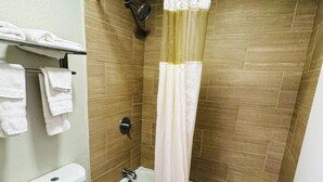 A bathroom with a toilet, bathtub, and shower curtain. - Newnan Lodge (Newnan)