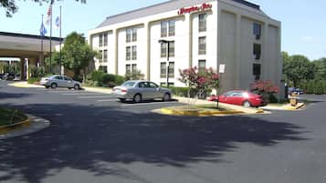 Ein Hampton Inn Hotel mit Parkplatz, mehreren Autos und Flaggen.