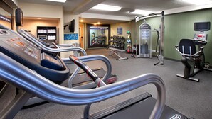A gym with treadmills, weight machines, and a TV screen.