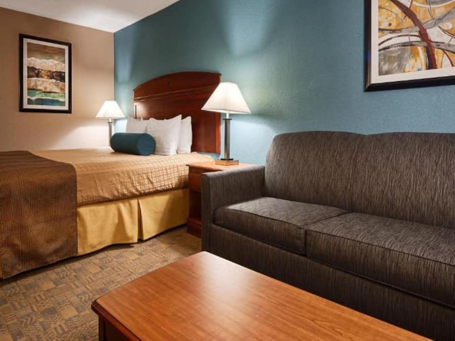 Ein Hotelzimmer mit Bett, einer Couch, einem Holztisch und einem Bild an der Wand.