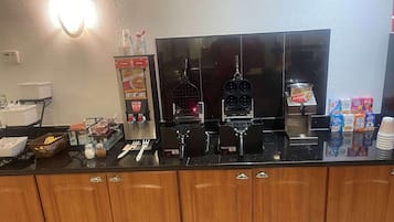 Angolo cottura con piastra per waffle, distributore di sciroppo e scatole di cereali.
