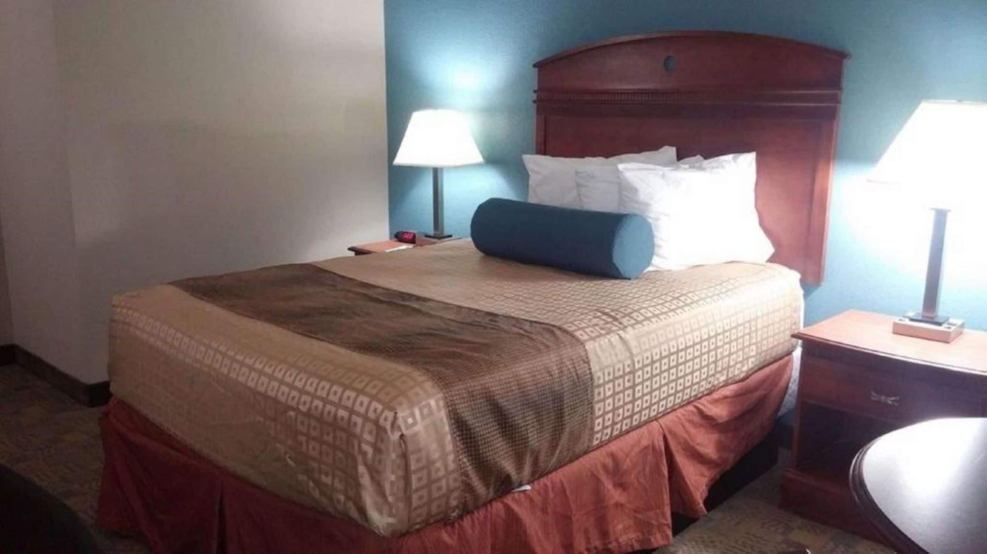 Una habitació d'hotel amb un llit, dues làmpades de nit, una taula de nit i una cadira.