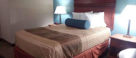 A hotel room with a bed, two bedside lamps, a nightstand, and a chair.