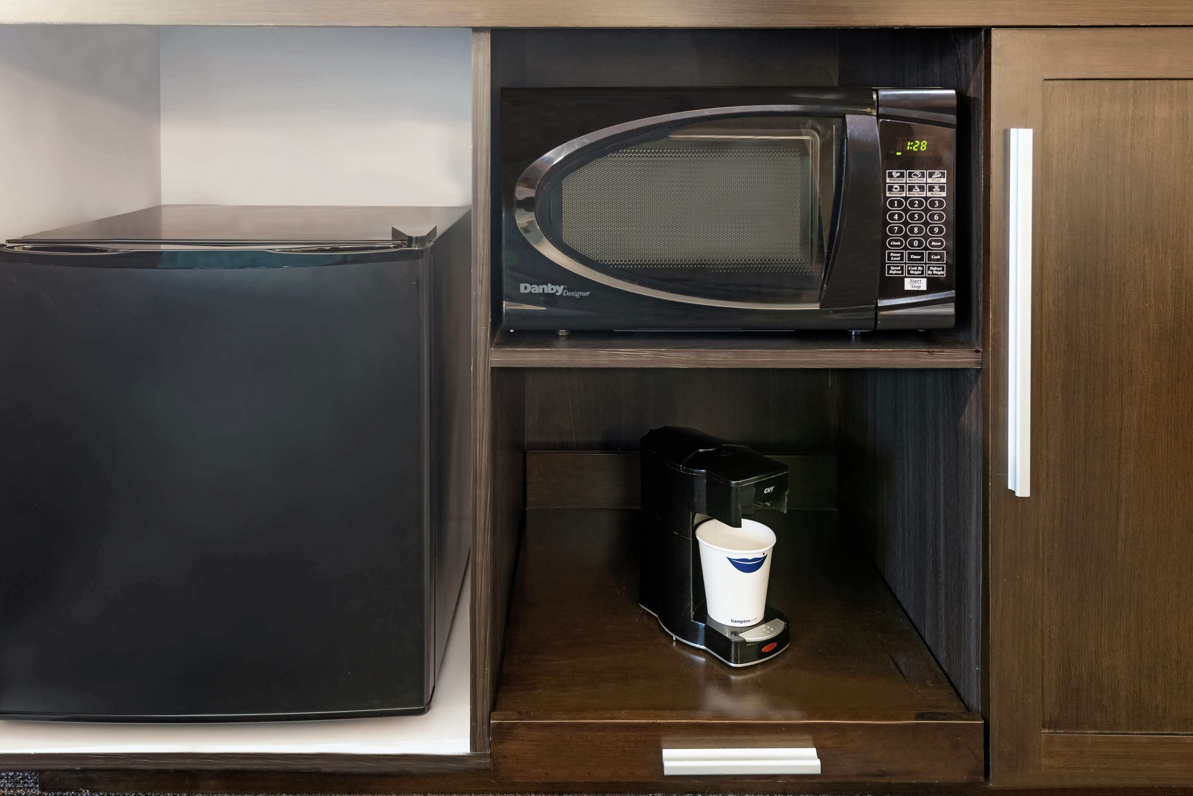 A kitchen with a black refrigerator, a microwave, and a coffee maker on the counter.