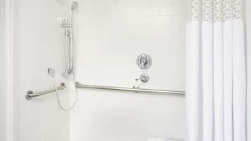 A bathroom with a shower, grab bar, and a small sink with a towel.