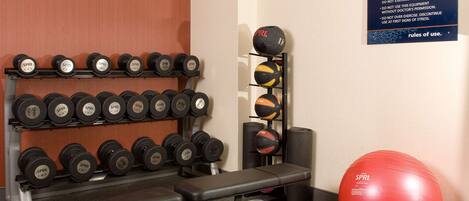 A gym with weightlifting equipment, a bench, and exercise balls.