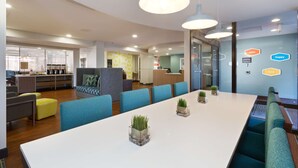 Un espacio de oficina moderno con una mesa larga, sillas azules y plantas en macetas.