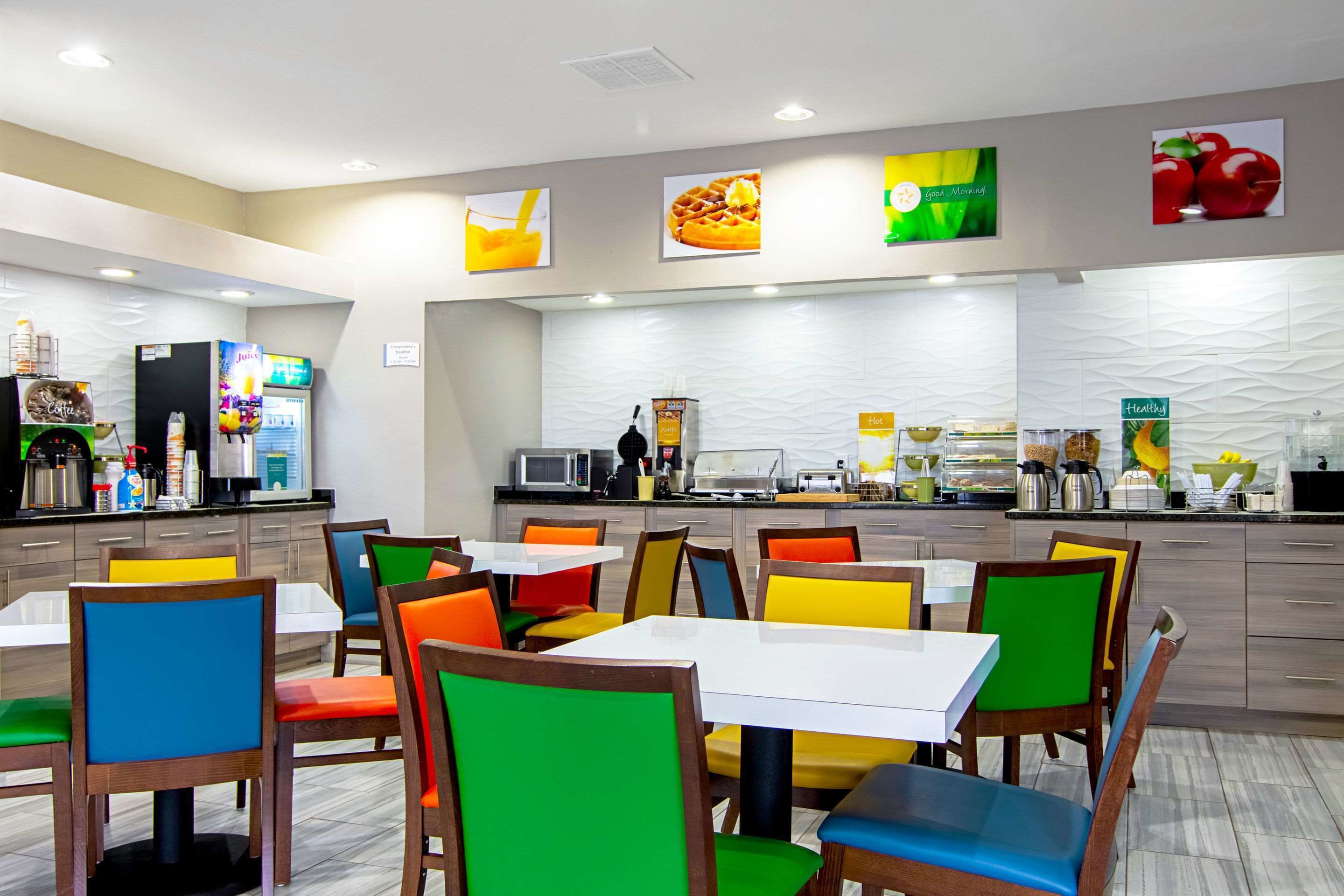 A modern restaurant with colorful chairs and tables, a counter with food and drink options, and a clean, well-lit interior.