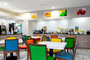A modern restaurant with colorful chairs and tables, a counter with food and drink options, and a clean, well-lit interior.