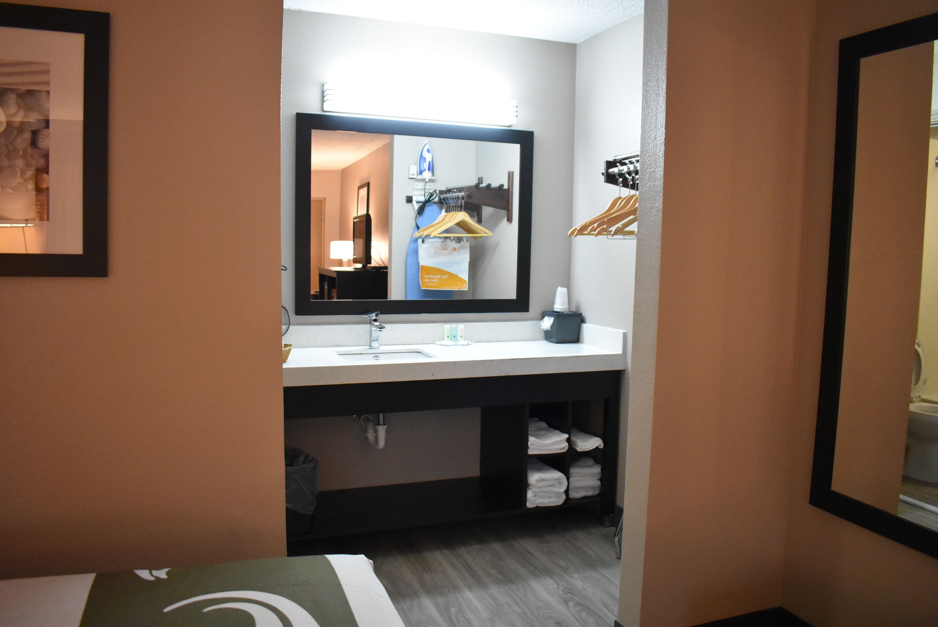 A hotel bathroom with a large mirror, a sink, and a towel rack.