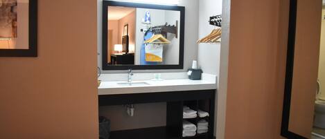 A hotel bathroom with a large mirror, a sink, and a towel rack.
