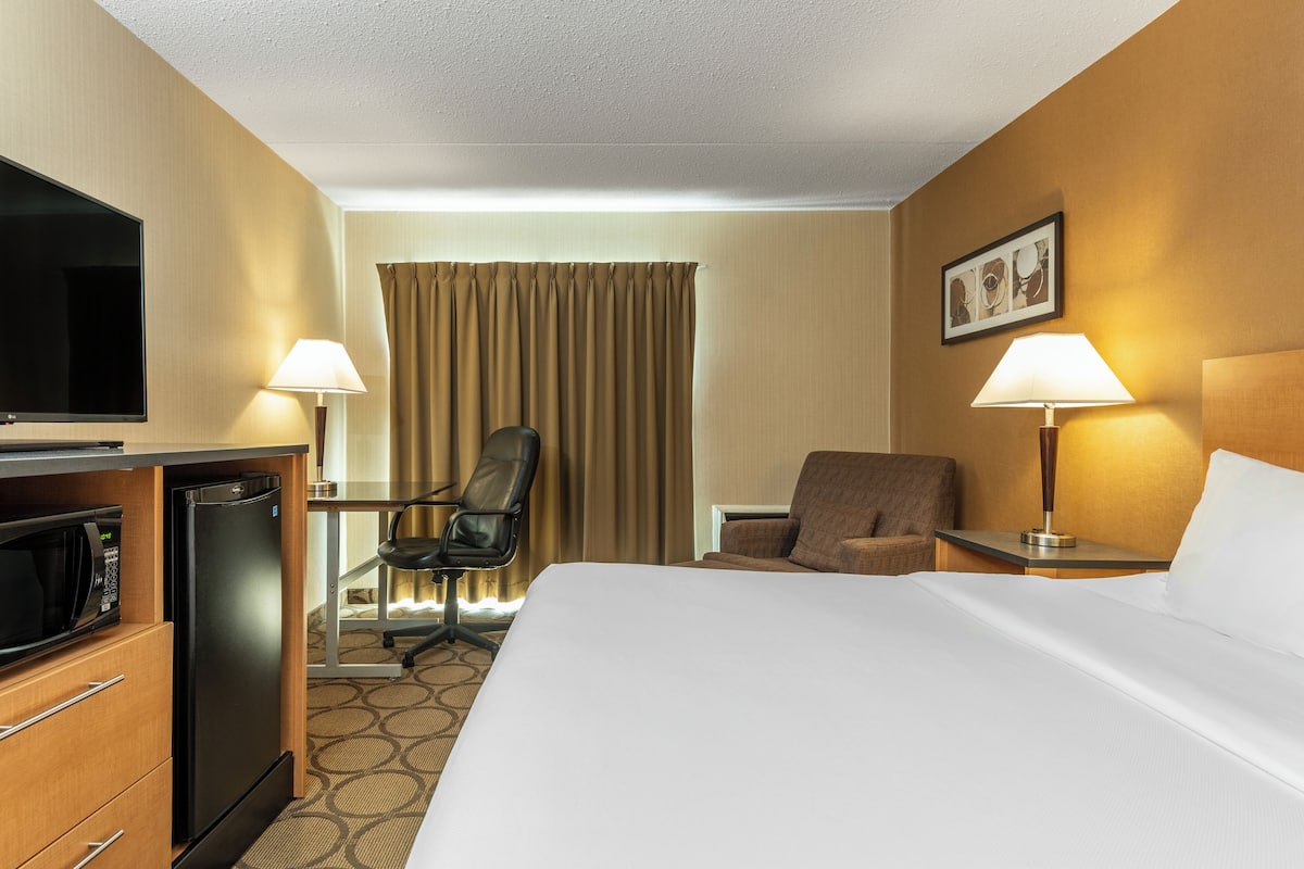 Une chambre d’hôtel équipée d’un lit, d’un bureau avec un ordinateur, d’un micro-ondes, d’une chaise et d’une télévision.