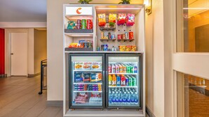 Máquina expendedora llena de aperitivos, bebidas y productos Smartfood en un hotel.