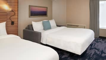 A hotel room with two beds, a gray sofa, a wall-mounted light, and a painting.