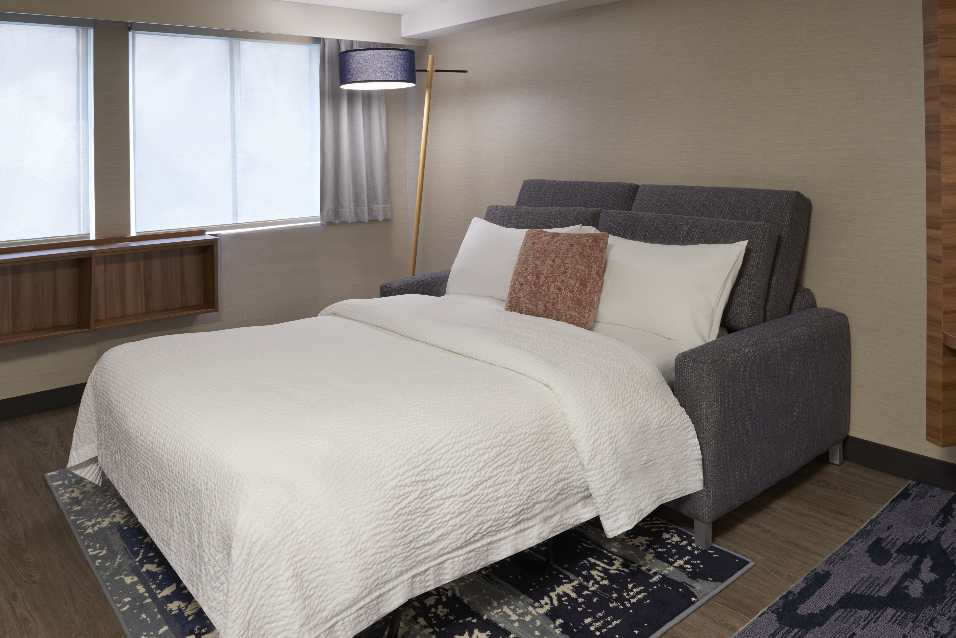 A modern bedroom with a bed, a floor lamp, and a window with curtains.
