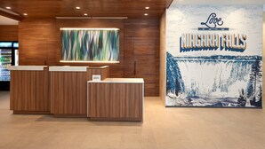 A reception area with wooden paneling, a large window with a view, and a wall mural of Niagara Falls. - Fairfield by Marriott Niagara Falls, Canada (Niagara Falls)