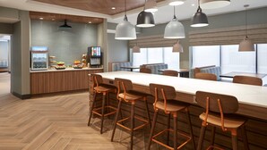 A modern bar area with a long counter, multiple stools, and pendant lighting. - Fairfield by Marriott Niagara Falls, Canada (Niagara Falls)