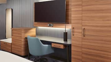A modern hotel room with a wooden desk, a blue chair, a flat-screen TV, and a built-in cabinet.