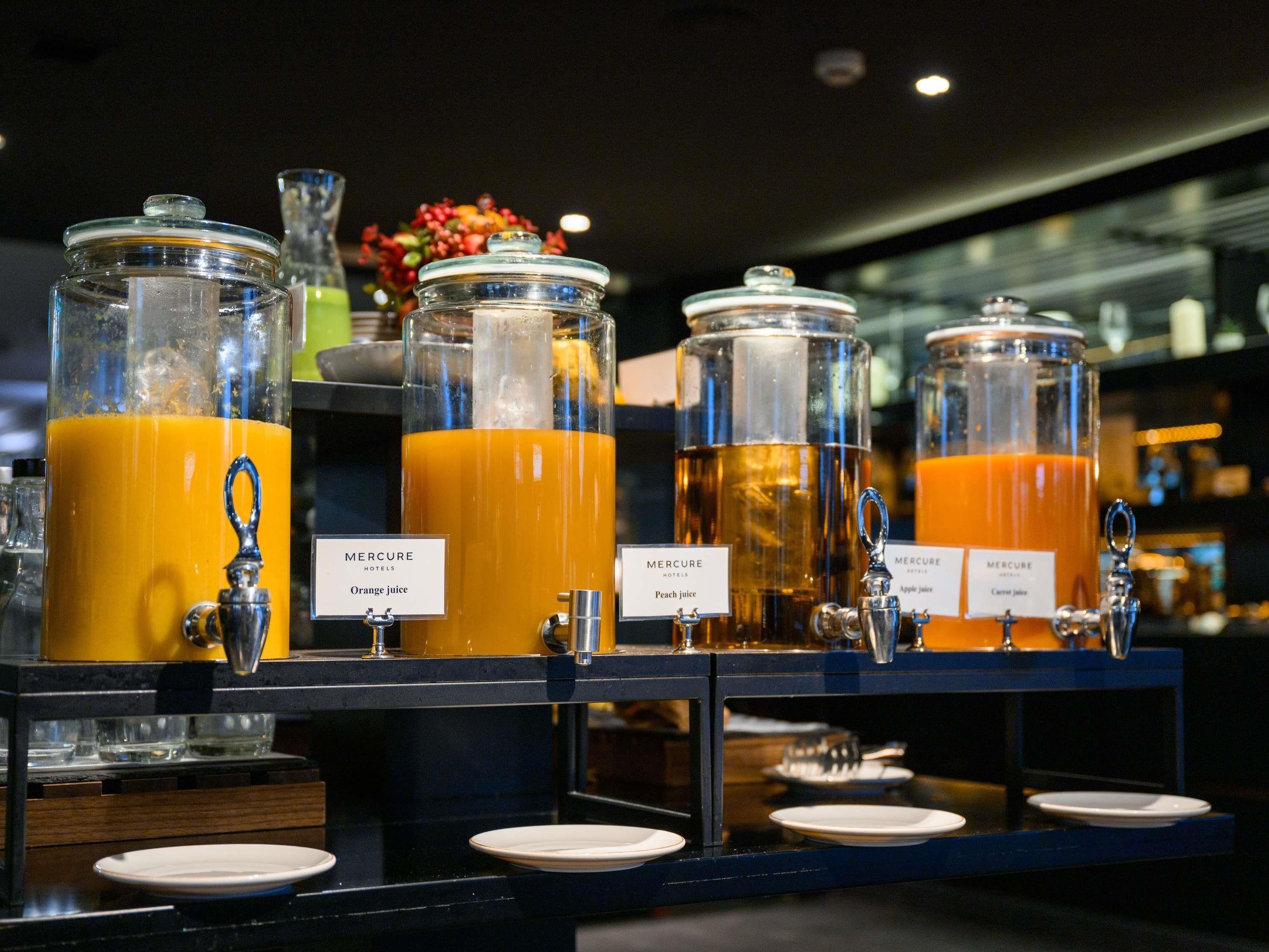 Ein Saftbar mit Spendern, auf denen 'Orangensaft', 'Pfirsichsaft' und 'Apfelsaft' stehen.