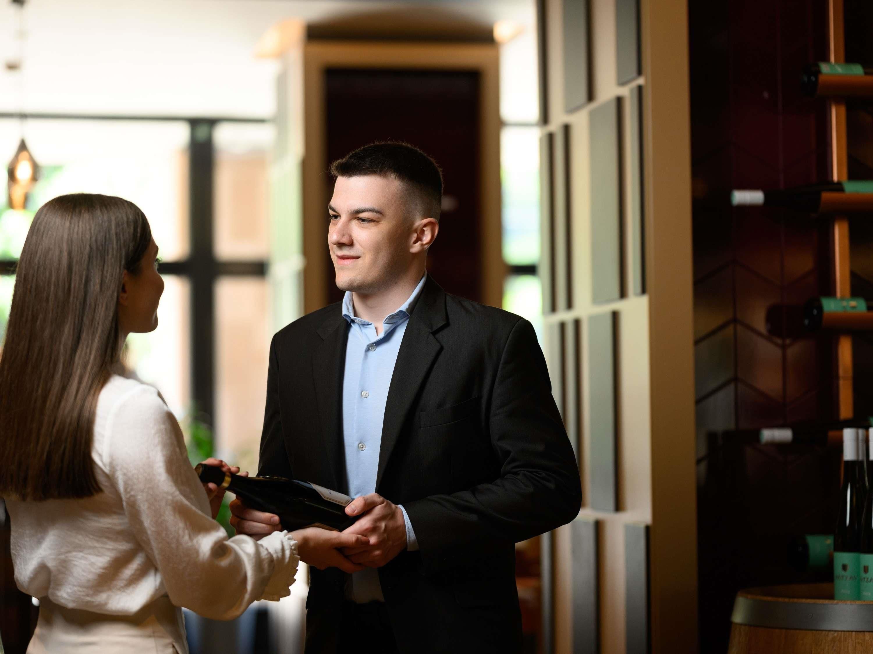 A man in a suit receiving a wallet from a woman.