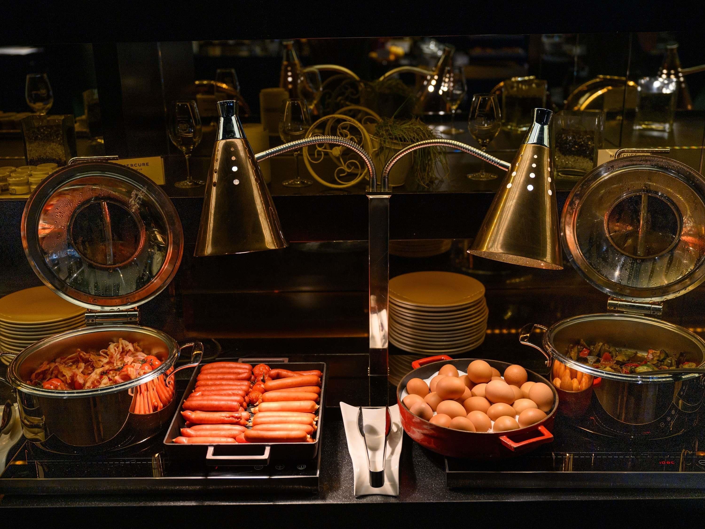 Een buffet met hotdogs, eieren en diverse gerechten.