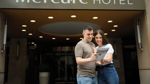 Um casal em frente à entrada do Hotel Mercure, olhando um mapa.