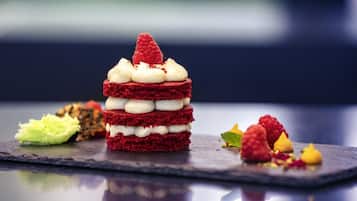 Un postre con varias capas y una frambuesa encima, sobre un plato de pizarra oscura.