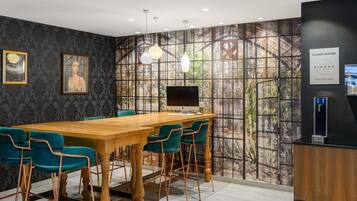 Une salle de conférence avec une longue table en bois, des chaises de couleur turquoise, un ordinateur de bureau et un distributeur d’eau.